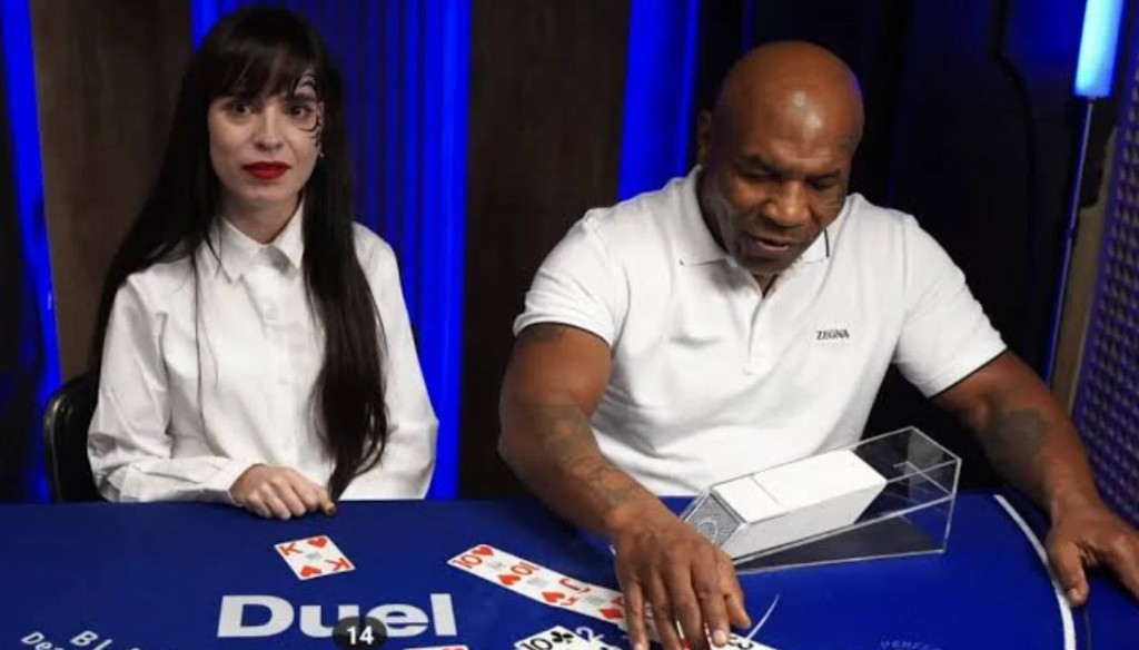 Mike Tyson dealing at the Duel blackjack table next to a croupier in white